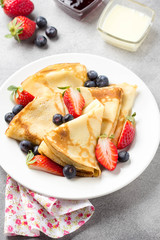 Wall Mural - Thin pancakes with strawberries and blueberries, jam, condensed milk, delicious Breakfast. Russian traditional dessert for Shrovetide celebration (maslenitsa). French crepes