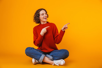 Wall Mural - Emotional young pretty woman posing isolated over yellow wall background showing copyspace.