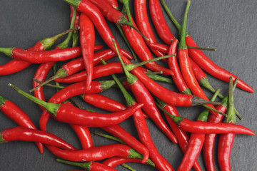 A lot of sharp hot spice red chilli cayenne pepper with wet drops of freshness water dew on a black graphite slate stone surface. Natural vegeterian diet organic vegetable. Dark food foto