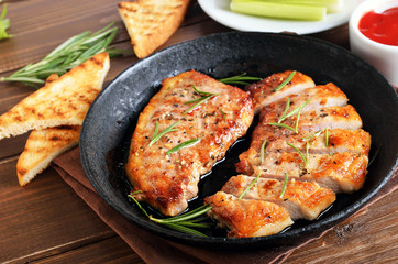 Roasted pork steaks in frying pan, toast and tomatoes sauce