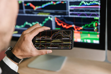 Fototapete - Portrait of successful businessman using smartphone while working with digital graphics on computer in office