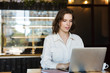 © Drobot Dean - Smiling young businesswoman sitting at the cafe indoors