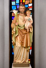 Statue Of Saint Joseph Foster Father Holding Infant Son Jesus And Lilies At Stained Glass Window In Saint Roch's Catholic Church Toronto Canada