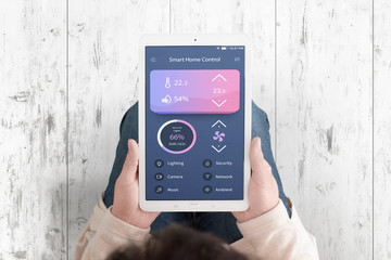 Wall Mural - Smart home control concept app on teblet in woman hands. Flat design interface. Top view. White wooden floor in background.