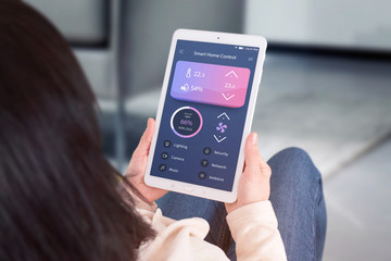 Poster - Smart home control automation app concept. Woman use tablet with modern flat desing app to control living room temperature, ventilation, lighting.