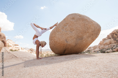 Desert Yoga Boulder Supported Scorpion Woman.  Scorpion Pose (Vrschikasana) is an advanced pose.