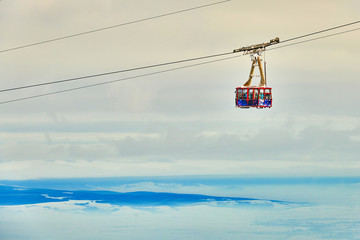 Cable car with skiers in Poiana Brasov ski resort,  ski slopes whit forest covered in snow on winter season