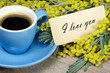 bouquet and a cup of coffee. mimosa flowers and a cup of coffee. coffee and a note i love you. inscription i love you