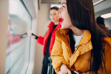 Young positive female looking window train.  Women Friendship Concept.