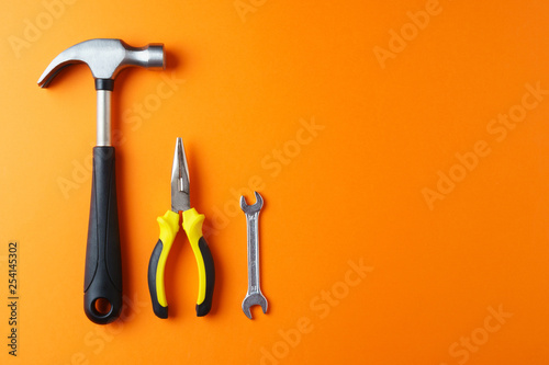 Fotomural Metal hammer, pliers, a key on an orange background