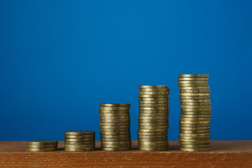 Stacks of metal coins on a blue background, close-up