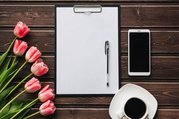Wall Mural - bouquet of pink tulips with a Cup of coffee and a smartphone on a wooden table