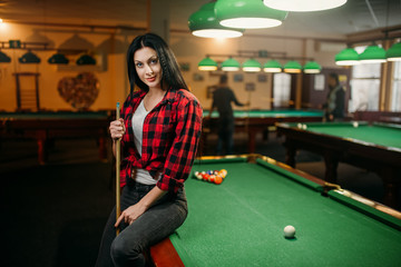 Wall Mural - Female billiard player with cue poses at the table