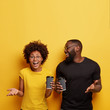 © wayhome.studio  - Positive black classmates have coffee break, hold paper cups, discuss future plans with happy expressions, share good news, stand shoulder to shoulder over yellow background, free space above