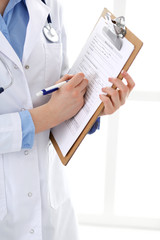 Wall Mural - Female doctor using medical form on clipboard closeup.  Physicianat work in hospital or clinic. Healthcare, insurance and medicine concept 