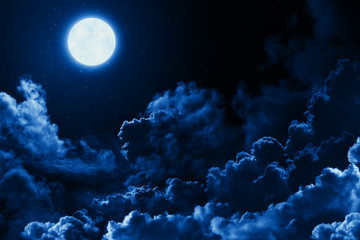 mystical bright full moon in the midnight sky with stars surrounded by dramatic clouds. dark natural