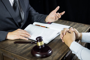 Lawyer or judge consult meeting with client at a law firm about legal legislation in courtroom with Judge gavel and Gold brass balance scale.