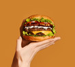 © Dmitry Lobanov - Woman hands hold big double cheeseburger burger sandwich with beef and bacon on yellow