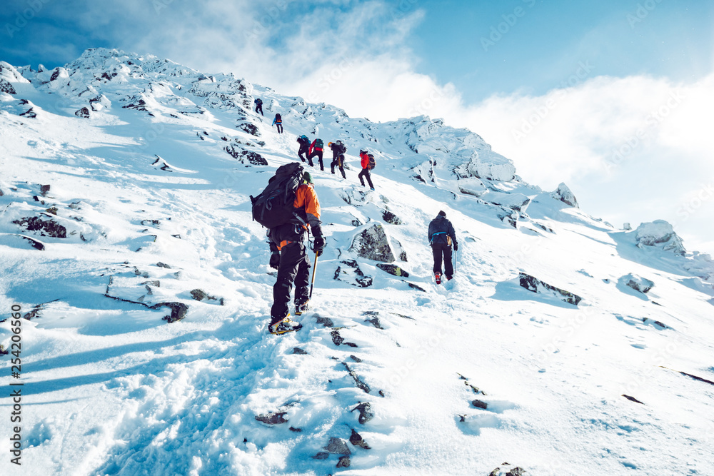 A group of climbers ascending a mountain in winter - obrazy, fototapety, plakaty 