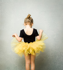 Little girl wearing leotard and tulle tutu viewed from behind