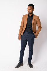 Full body shot of young African businessman thinking and looking down