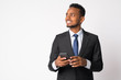 Happy young handsome African businessman thinking while using phone