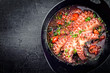 Traditional Greek octopus braised cooked with tomatoes and herbs in ouzo sauce as top view in a cast-iron saucepan with copy space left