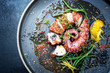 © HLPhoto - Traditional French octopus braised cooked with Salicornia, lemon curd and spice as top view on a modern design plate with copy space left