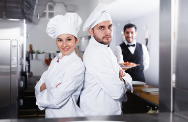 Portrait of professional chefs in kitchen on background