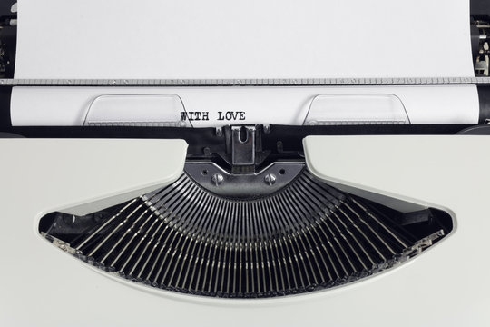 Old retro obsolete white typewriter with close-up typing text With Love as heading on paper