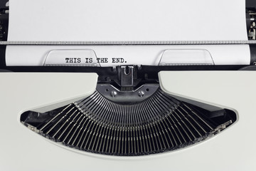 Fototapete - Old retro obsolete white typewriter with close-up typing text This is the end as heading on paper