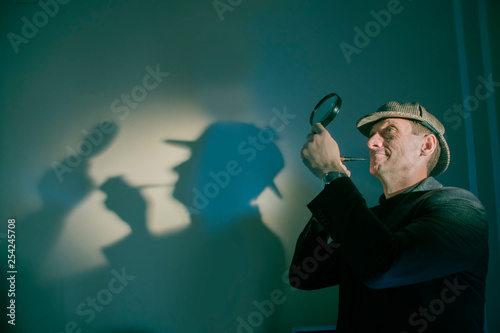 Fotografía detective at work with magnifying glass and pipe investigating crimes