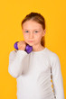 © andov - Young and athletic girl does physical exercises with dumbbells, on a yellow background