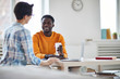 © Seventyfour - African-american businessman with drink looking at colleague during convervsation by workplace at break