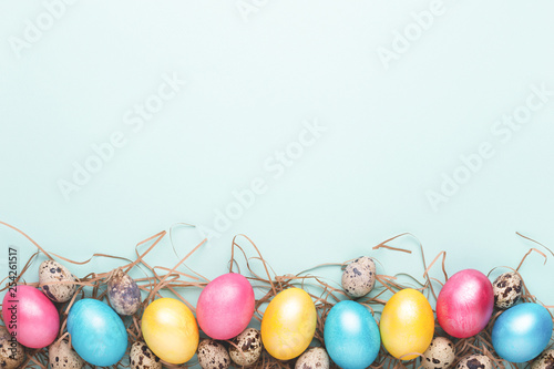 Border made of colorful Easter eggs on turquoise background. Top view, copy s...