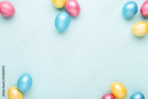 Frame made of colorful Easter eggs on turquoise background. Top view, copy sp...