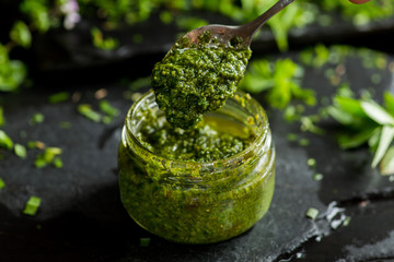 pesto sauce in a spoon, jar with pesto sauce