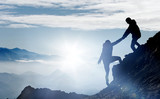 Fototapeta Miasto - Mountaineers help each other to reach the summit