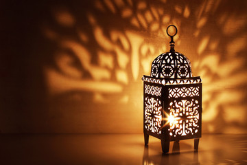 Wall Mural - Silhouette of Moroccan ornamental lantern with burning glowing candle. Decorative shadows. Festive greeting card, invitation for Muslim holy month Ramadan Kareem. Festive night background.