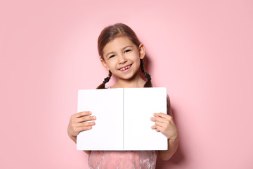Cute little girl with book on color background