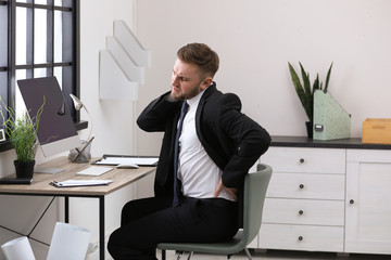 Wall Mural - Businessman suffering from back pain at workplace