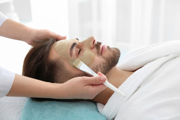 Poster - Cosmetologist applying mask on client's face in spa salon