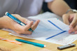© smolaw11 - Students using pen reading information on white paper in high school, Asian exams room, Tests or examination is assessment intended to measure knowledge, skill, aptitude, Education study Concept