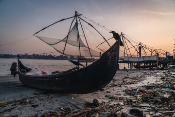 Chinese fishing nets during the Golden Hours at Fort Kochi, Kerala, India sunrise bird over the boat