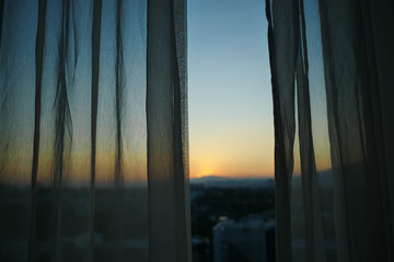 Wall Mural - sunlight through white curtain with sunset sky view outside the window
