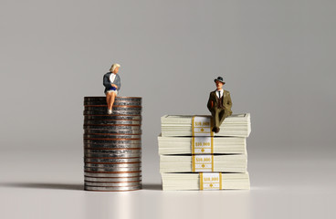 Wall Mural - The concept of gender pay gap. A pile of bills and coins. Miniature people.