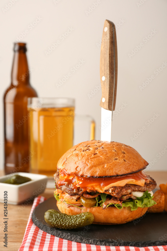 Tasty burger with knife on table