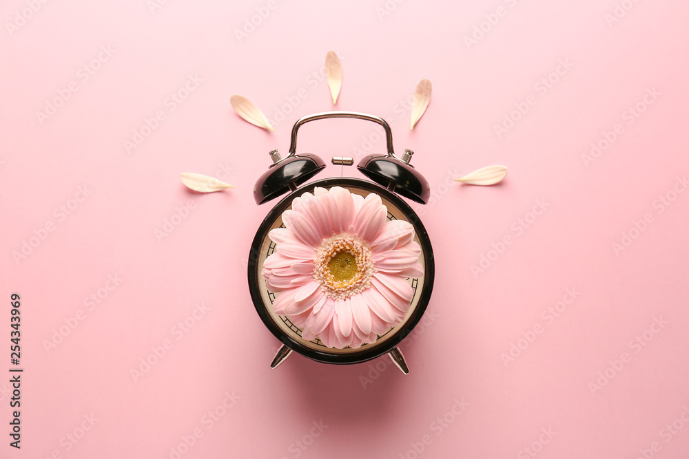 Alarm clock with flower on color background - obrazy, fototapety, plakaty 