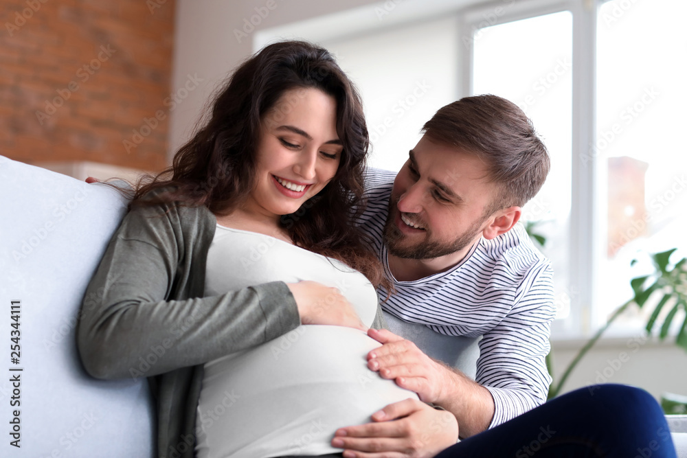 Happy pregnant couple resting at home