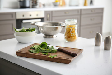 Fresh herbs with cutting board on table in kitchen